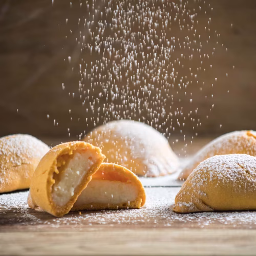 Empanadas de leche | Pastelería Ciro Guatemala | Elaboradas con masa de harina de arroz, suave y ligeramente crujiente, estas empanadas encierran un generoso relleno de manjar de leche perfumado con canela y pasas. Una receta de herencia italiana que evoca el calor del hogar desde hace más de 50 años.