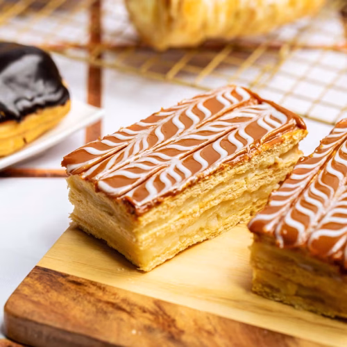 Napoléon | Pastelería Ciro Guatemala | Elegante pastel napoleón de capas crujientes de hojaldre horneado con mantequilla, intercaladas con suave manjar de leche y coronadas con una cobertura de cajeta artesanal de profundo sabor acaramelado. Una pieza de repostería clásica con carácter.