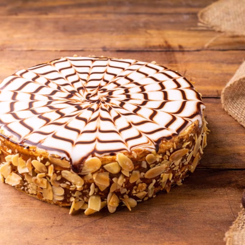Torta Chilena | Pastelería Ciro Guatemala | Clásica torta chilena de múltiples capas de hojaldre crujiente rellenas con cajeta artesanal de sabor profundo, bañada en fondant suave y decorada con lascas de almendra tostada alrededor. Una pieza de repostería tradicional que nunca pasa de moda.