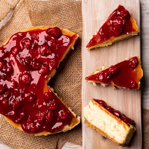 Cheesecake de cereza | Pastelería Ciro Guatemala | Cheesecake horneado a baja temperatura con una base crujiente de galleta, relleno de queso crema suave y aterciopelado, cubierto con salsa de cereza de sabor intenso y color profundo. Cremoso, equilibrado y elegante en cada porción.