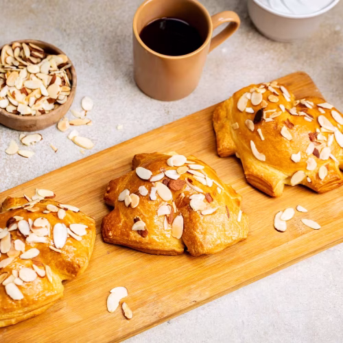 Danese de almendra | Pastelería Ciro Guatemala | Pieza de pastelería danesa de masa laminada a base de mantequilla, rellena de manjar de leche artesanal y cubierta con almendras laminadas tostadas. Una combinación de sabor suave y textura crujiente que refleja la tradición de la pastelería europea.