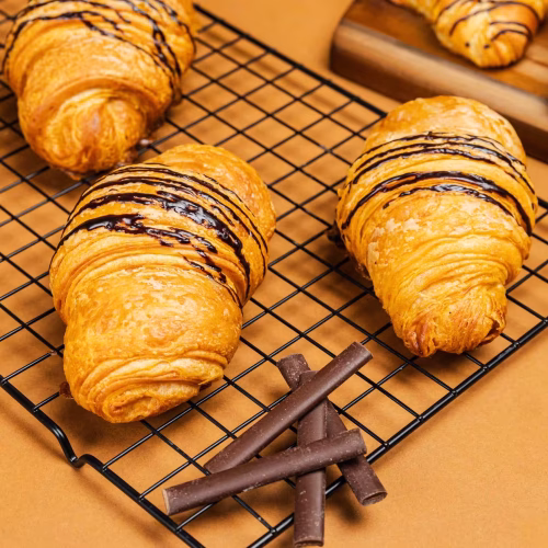 Croissant de chocolate | Pastelería Ciro Guatemala | Croissant artesanal elaborado con nuestra masa laminada especial a base de mantequilla importada, fermentado y horneado lentamente para lograr capas aireadas y doradas. Relleno con dos generosas barras de chocolate para un resultado indulgente en cada bocado.